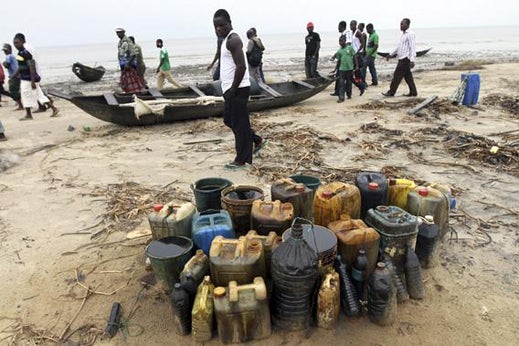 Villagers walk past jerrycans containing crude oil at the shore of the Atlantic ocean near Orobiri village, days after Royal Dutch Shell's Bonga off-shore oil spill in Nigeria's delta.